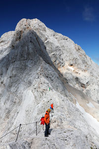 Low angle view of man climbing on mountain against clear sky