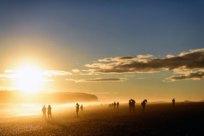 People on beach against sky during sunset