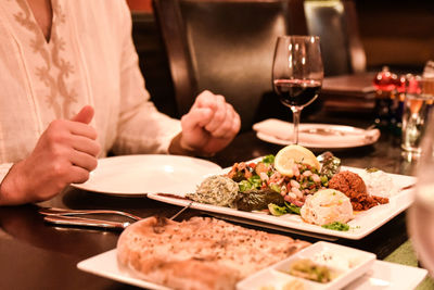 Midsection of person with food and drink at restaurant table