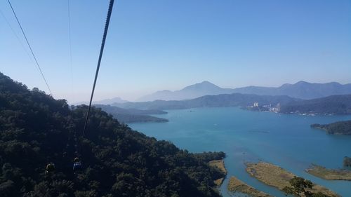 Scenic view of sea and mountains against clear blue sky