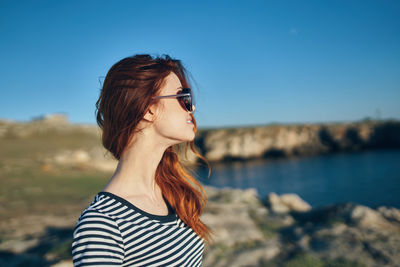 Portrait of young woman wearing sunglasses standing against sky