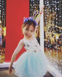 Portrait of cute girl wearing dress dancing against illuminated lights