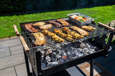 Different types of meat fried on the home grill, standing on a home garden on the paving stone.