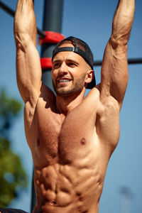 Low angle view of shirtless man exercising against sky