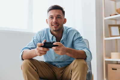 Portrait of young man using phone while sitting on sofa at home