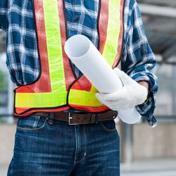 Midsection of man holding umbrella standing outdoors