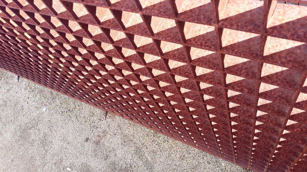 HIGH ANGLE VIEW OF METAL PATTERN ON FOOTPATH