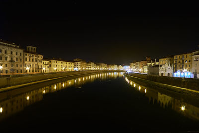 Illuminated bridge over river by buildings in city at night