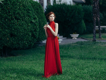 Portrait of woman standing on grass against trees