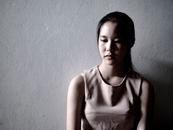 Portrait of a beautiful young woman standing against wall