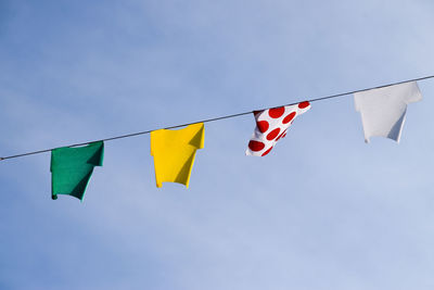 Low angle view of flags hanging against blue sky