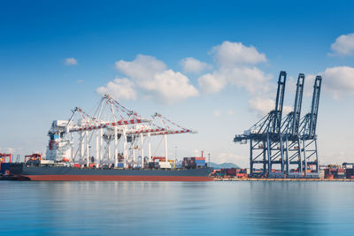 Cranes at commercial dock against sky