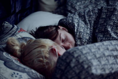 Close-up of sisters sleeping on bed