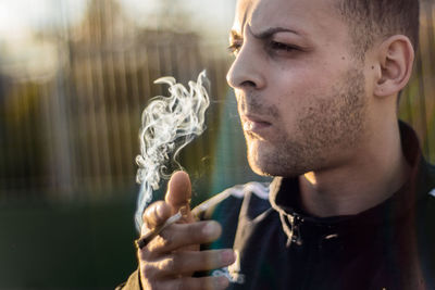 Man looking away while smoking marijuana joint