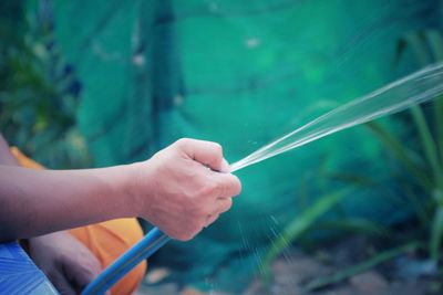 Cropped hand of man spraying water through pipe