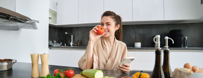 Portrait of smiling young woman drinking juice at home