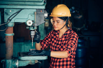 Midsection of man working in metal machine