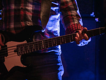 Midsection of musician playing guitar at music concert