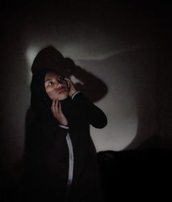 Portrait of a young woman standing against wall