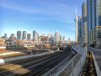 Railroad tracks amidst buildings in city against sky