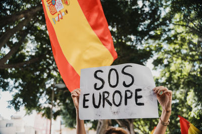 Low angle view of woman holding flag against trees