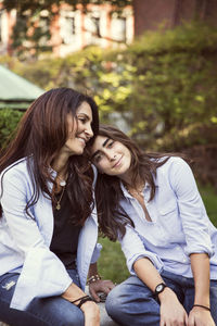 Smiling mother and daughter resting at park