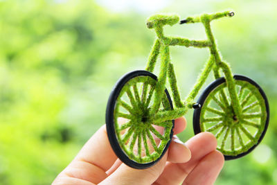 Cropped fingers of person holding toy bicycle