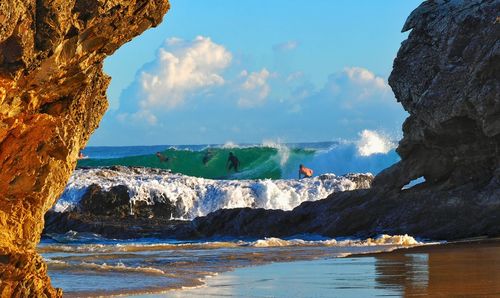 People surfboarding on sea by against sky