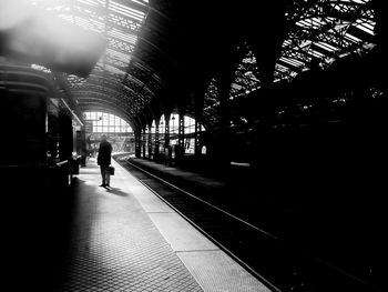 Rear view of man walking on railroad station platform