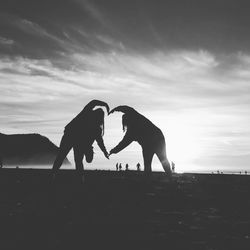 Two women making a heart shape on beach