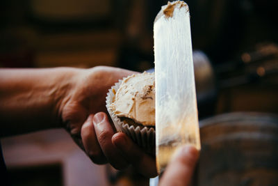 Close-up of hand putting icing on cupcake