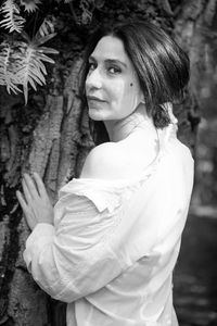 Side view of young woman standing against trees