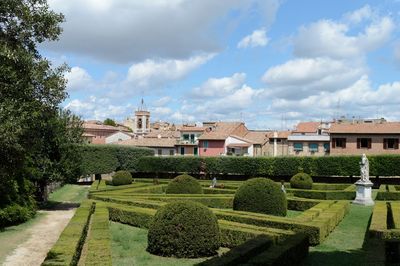 View of garden with buildings against cloudy sky