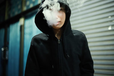 Portrait of young man smoking while standing outdoors