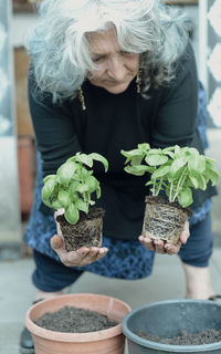 Portrait of woman holding potted plant