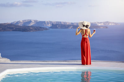 Rear view of woman standing by sea against sky