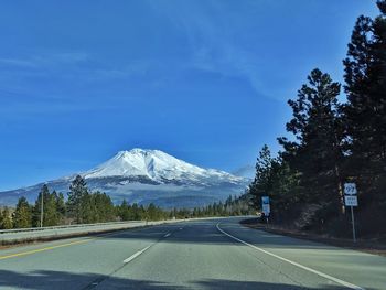 Road by snowcapped mountains against sky