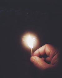 Close-up of hand holding lit candle