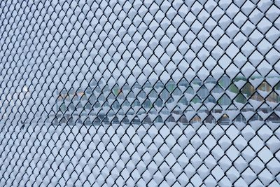Full frame shot of snow covered chainlink fence against sky