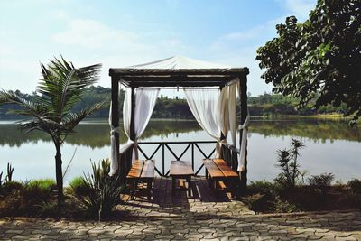 Gazebo by lake against sky