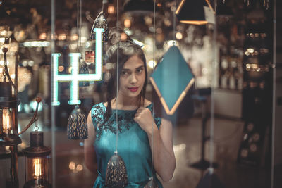 Young woman standing against illuminated lights at night