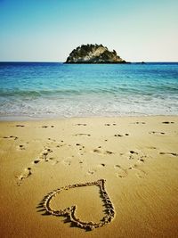 Heart shape drawn at beach against clear sky