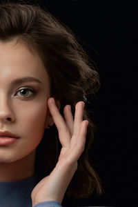 Close-up portrait of a beautiful young woman over black background
