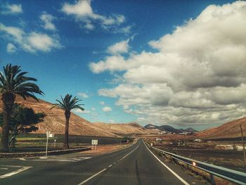 Empty road against cloudy sky