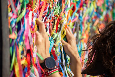  a person's hands are tying a souvenir ribbon on the railing of the senhor do bonfim church