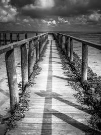 Footpath leading towards bridge against sky