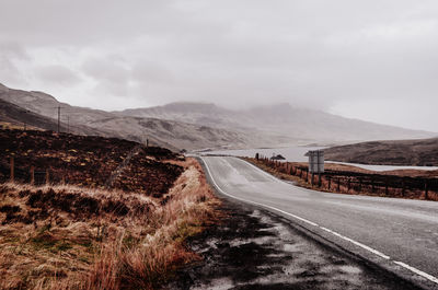 Scenic view of road by mountains against sky