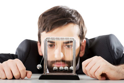 Portrait of man holding camera on table against white background
