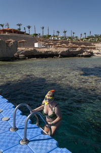 Plump girl in a green swimsuit and a swimming mask, dives and swims in the sea