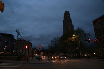 Illuminated city street against sky at night